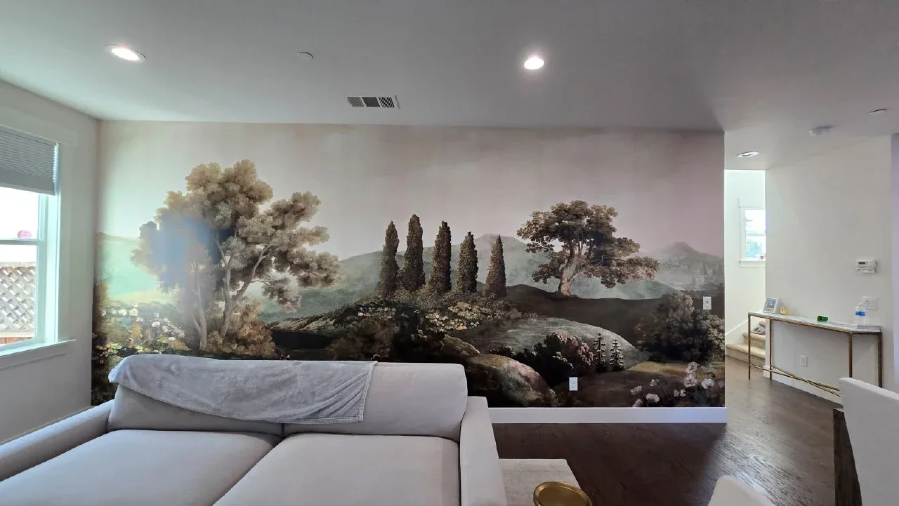 A pale scenic landscape mural spanning the wall behind a light-colored sofa